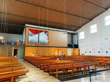 Dachau, Almanya - 22 Eylül 2022: Ahşap sıralar, org galerileri ve parlak pencerelerin yer aldığı bir Alman kilisesinin iç görünümü. Heilig Kreuz, Dachau. 