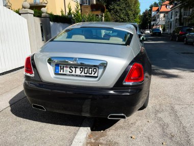 Münih, Almanya - 23 Eylül 2022: Modern evleri ve yeşillikleri olan sessiz bir Alman caddesinde zarif Rolls Royce Wraith.