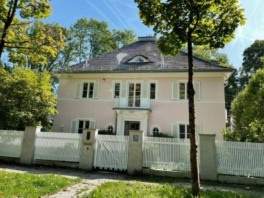 Münih, Almanya - 23 Eylül 2022: Beyaz çitli, yemyeşil ve güneşli mavi gökyüzü ile Almanya 'da büyüleyici bir ev.