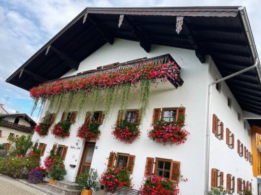 Waging am See, Almanya - 25 Eylül 2022: Canlı çiçek sepetleri, ahşap kepenkleri ve karşılayıcı bir Alp cazibesi olan pitoresk bir Alman evi.