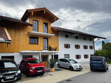 Waging am See, Almanya - 25 Eylül 2022: Ahşap bir üst perdeli ve beyaz alt katlı, çok sayıda park etmiş arabası olan Alman malikanesi.