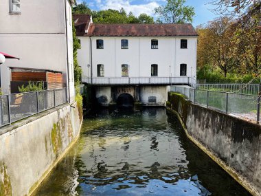 Furstenfeldbruck, Almanya - 26 Eylül 2022: Furstenfeldbruck, Almanya 'da su üzerinde beyaz bir bina ve kemerli açılışlar içeren büyüleyici kanal sahnesi.