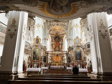 Andechs, Almanya - 27 Eylül 2022: Andechs, Almanya 'da Barok Kilisesi yaldızlı sunak, dini tablolar ve kilise sıralarında tek bir kişi.