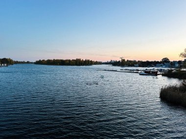 Viyana, Avusturya - 22 Ekim 2024: Huzurlu göl manzarası Viyana, Avusturya 'da tekne, sakin su ve sakin nehir kenarı topluluğunun yer aldığı.