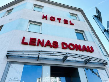 Viyana, Avusturya - 22 Ekim 2024: Avusturya 'nın başkenti Viyana' da berrak gökyüzü altında, modern mavi beyaz bir binanın üzerinde koyu kırmızı işareti bulunan bir otel cephesi.