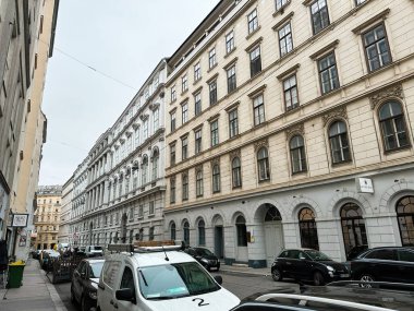 Viyana, Avusturya - 22 Ekim 2024: Viyana, Avusturya 'da sakin bir Avrupa bulvarı boyunca klasik mimari ve park halindeki arabalarla kent sokak sahnesi.