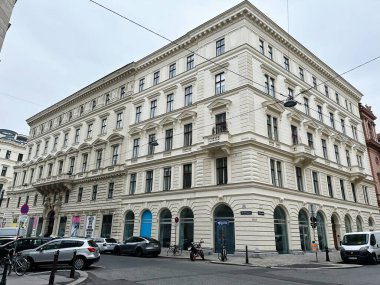 Viyana, Avusturya - 22 Ekim 2024: Meşgul şehir caddesinde kemerler, balkonlar ve Avusturya 'nın Viyana kentinde klasik mimari ayrıntıların yer aldığı zarif beyaz cephe binası.