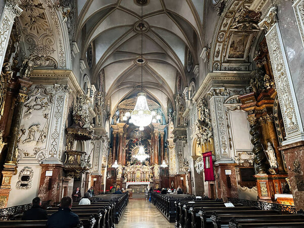 Vienna, Austria - October 22, 2024:  Luxurious Franciscan Church nave featuring intricately carved walls, statues, and a bright central altar in Vienna, Austria.