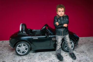 Çocuk üstü açık bir arabada oturuyor.