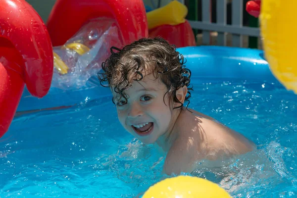 Boy playing and having fun in inflatable pool at home
