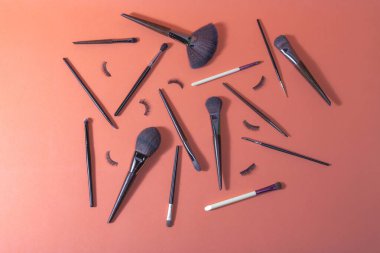 Profesyonel kullanım için farklı makyaj fırçaları ve takma kirpikleri olan turuncu yüzey