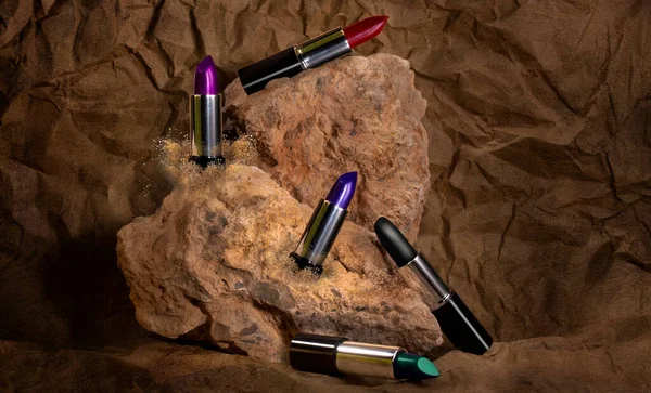 Farklı renkte ruj seti bir mağaranın içinde ve düzgün bir şekilde bir kaya oluşumunun üzerine yerleştirilmiş.,