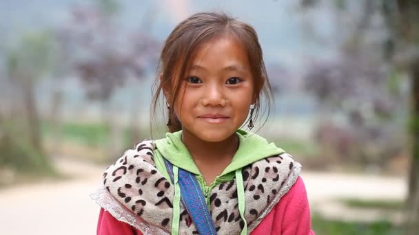 Sapa, Vietnam - 30 de noviembre de 2016: Una niña del grupo étnico de Hmong posa al extranjero para la cámara. Los niños a menudo posan para este propósito para ganar la recompensa o para vender los recuerdos . — Vídeos de Stock