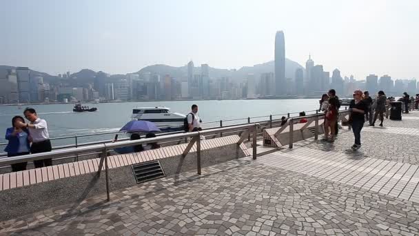 HONG KONG, HONG KONG - ABRIL 10,2017: Muchos turistas están caminando y tomando fotos desde la plataforma de observación. Vista turística del puerto de Victoria y de los modernos rascacielos de Hong Kong desde el muelle de Kowloon — Vídeos de Stock