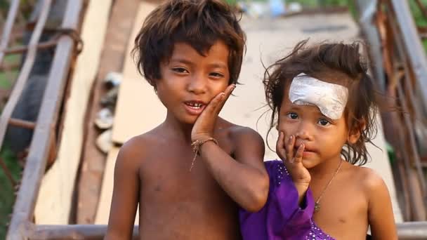 Siam Reap, Camboya - 14 de enero de 2017: Un niño sin hogar con su hermana pequeña viviendo en una casa de cajas vacías y escombros de construcción . — Vídeo de stock