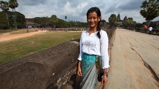 Siam Reap, Kambodja - 12 januari 2017: Unga kambodjanska flicka i traditionella kläder på bakgrunden av huvudentrén till Angkor Wat. — Stockvideo