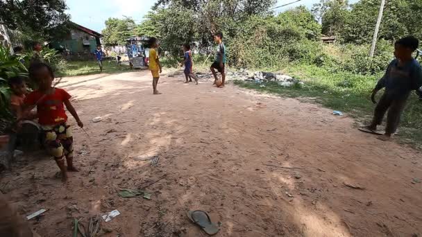 Siam Reap, Camboya - 13 de enero de 2017: Los niños camboyanos juegan al fútbol en la carretera en su pobre pueblo. Vivir en asentamientos y barrios pobres en Camboya — Vídeo de stock