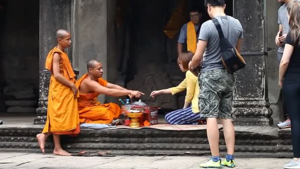 Siam Reap Angkor Wat, Cambodia - January 12, 2017:Cambodian buddhist monk reading mantra for tourist.Tourists and pilgrims leave donations for the preservation and restoration of complex Angkor Wat — Stock Video