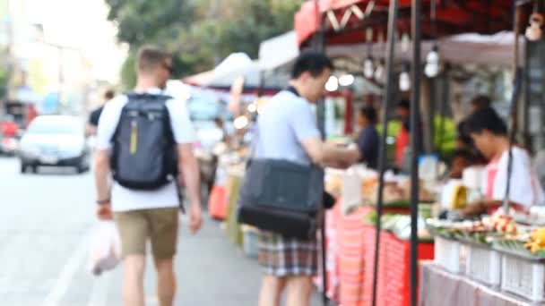 Gata matmarknad i Asien. Asiatisk mat. Abstrakta oskärpa turist köper Asian street food — Stockvideo