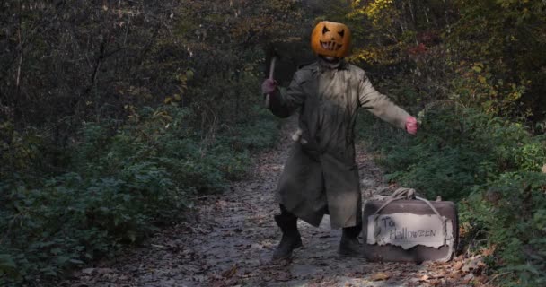 Zombie pumpkin goes on Halloween with a suitcase and an ax. — Stock Video