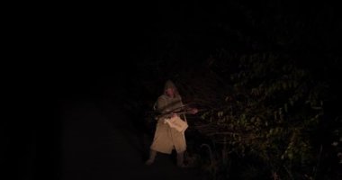 Cadılar Bayramı Zombi bir tırp ile ve bir yağmurluk ile yol boyunca gece hareket eder