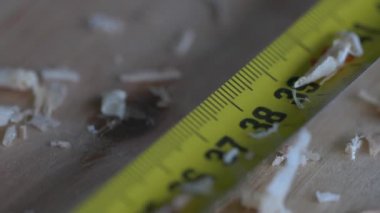 Sarı mezura yakın çekim görüntüsü işaretleniyor. Katılımcılar işe yarar. Marangoz iş başında. Süper yavaş çekim ölçüm bandı