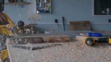 Bir marangoz, marangozluk atölyesinde elektrikli bir planlamacıyla çalışır. Doğal ışık çerçeveli yavaş çekim görüntüleri.