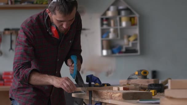 Jovem mestre carpinteiro em processo de trabalho em sua oficina de carpintaria . — Vídeo de Stock