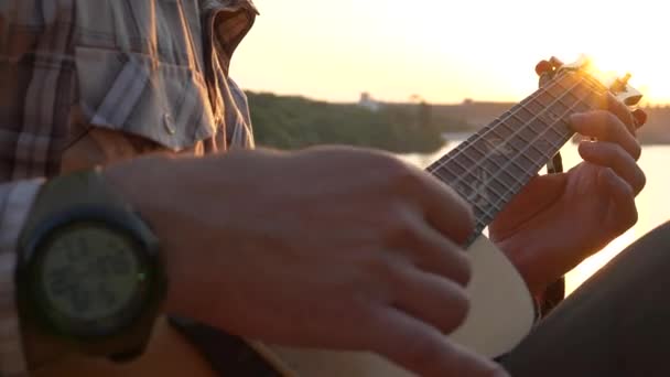 Um músico toca no ukulele close-up de suas mãos e no painel de uma guitarra. — Vídeo de Stock