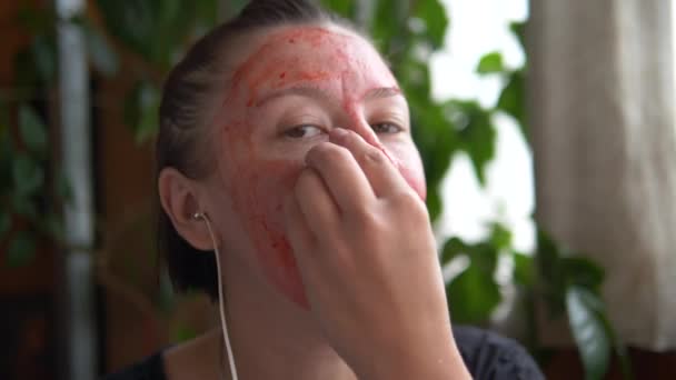 Soins du visage. La fille fait un masque naturel de fraise de baies à la maison. — Video
