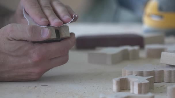 Stolarz poleruje przyjazne dla środowiska drewniane zabawki papierem ściernym w stolarni. — Wideo stockowe