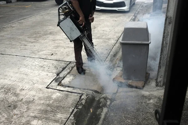 Munkavállaló ködös lakó-és egészségügyi szennyvízcsatorna terület rovarirtó, hogy megöli Aedes szúnyog tenyésztési földön, — Stock Fotó