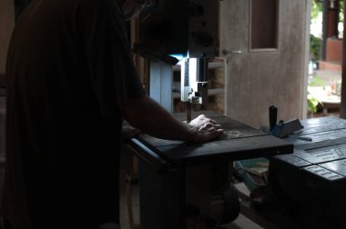 Marangoz üreticisi elektrikli yapboz ve ahşap ile çalışıyor. Ahşap işçisi bir odun parçası kesme  