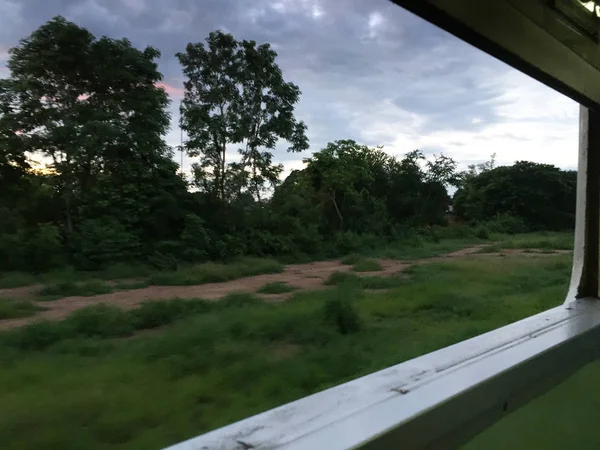 View from train window in motion of countryside and sky on sunny warm , in Thailand