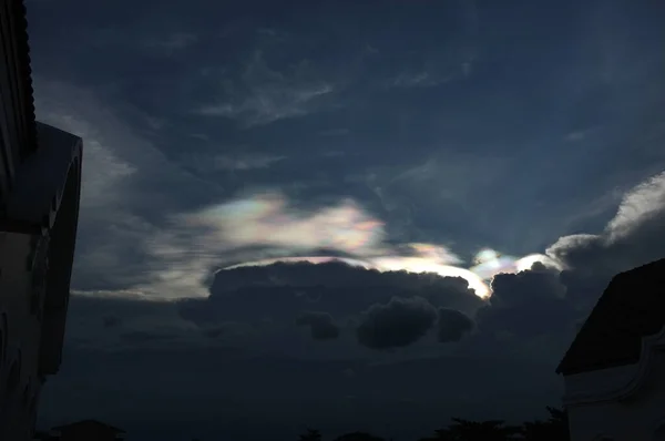 Rainbow beams over clouds on blue sky blackground