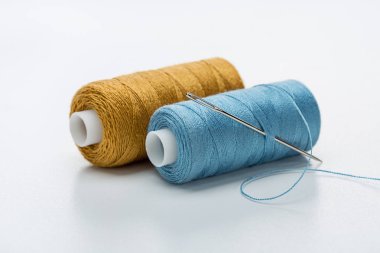 İki iplik bobinleri. Mavi iş parçacığı büyük iğne. Yakın çekim, ışık arka plan, kopya alanı.