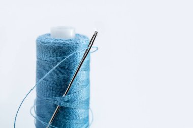 Reel aneedle ile mavi iş parçacığı. Yakın çekim, kopya alanı, ışık arka plan.