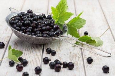 Kevgir, taze çilek ve yeşil siyah frenk üzümü tahta masada bırakır. Üstten görünüm, kopya alanı.