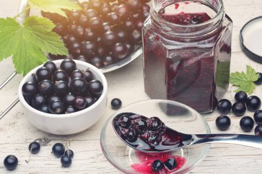 Reçel veya marmelat siyah frenk üzümü ve Frenk üzümü hafif zemin üzerine yeşil yaprakları ile.