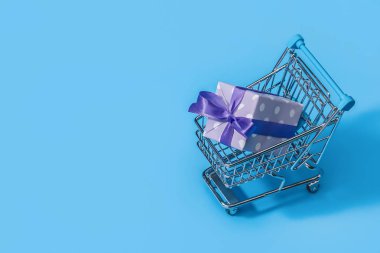 Alışveriş sepeti içinde güzel ve zarif kağıt ambalaj hediyeleri. Mor Şerit, puantiyeli kağıt. Kopya alanı.