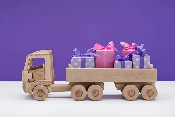 Gifts for Christmas, packed in box, wrapped in purple paper polka dot . Toy truck, holiday shopping.