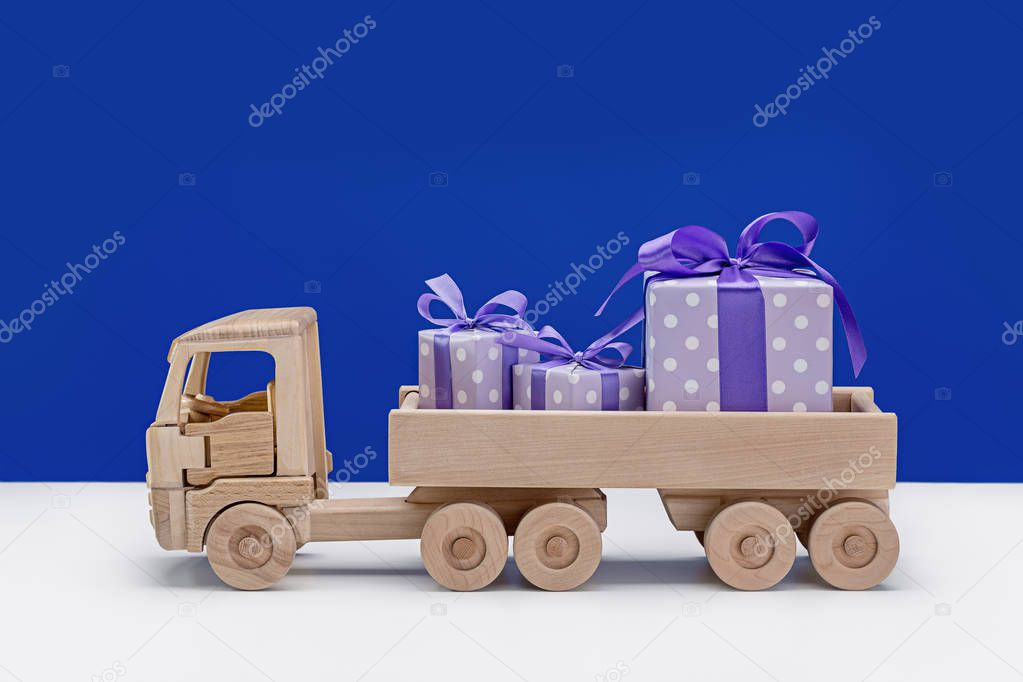 Truck with gifts in elegant paper on blue background. Surprises for Christmas, New Year, birthday, Valentine's Day. Copy space. Winter background.