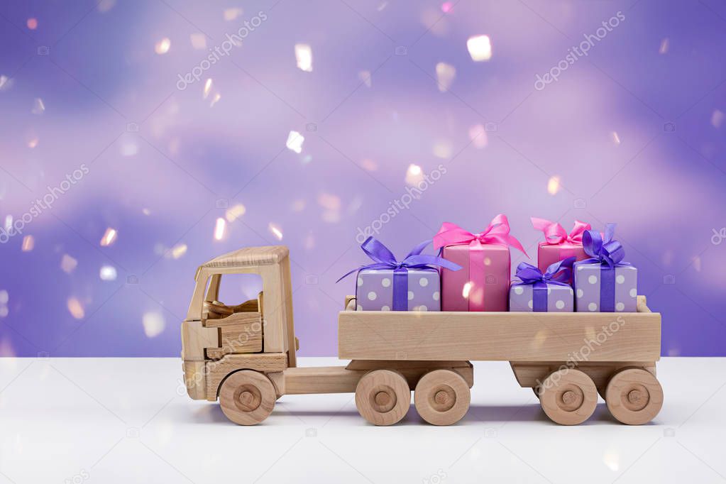 Truck with gifts in elegant paper on violet background with snowflakes. Surprises for Christmas, New Year, birthday, Valentine's Day. Copy space. Winter background.