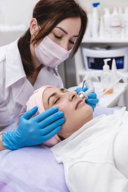 Güzellik uzmanı, güzellik salonları içinde güzel bir genç kadın cilt için phonophoresis yordam gerçekleştirir. Kozmetik ve profesyonel Cilt Bakımı.