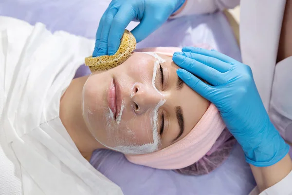 Model getting cleansing peeling rejuvenating facial treatment in a beauty SPA salon. Exfoliation, peeling and hydration. Close up.