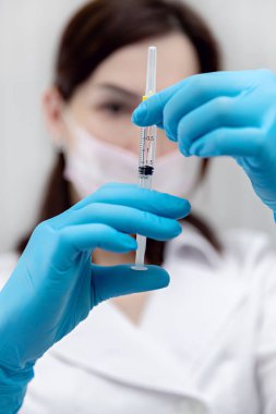 Şırınga maskeli kadın doktorun elinde enjeksiyon için.