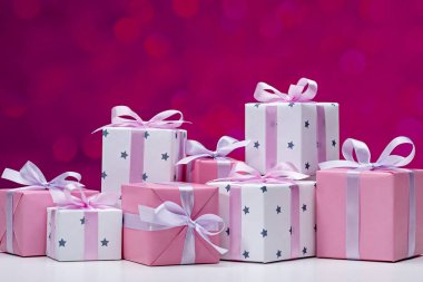 Koyu kırmızı arka planda hediye kutuları, bokeh. Pembe ve beyaz kağıt, yay ile saden kurdele ile dekore şık modern hediyeler. Kopyalama alanı