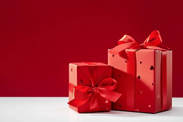 Red boxes with gifts on red background and white table. Copy space. Concepts of holidays and greeting cards.
