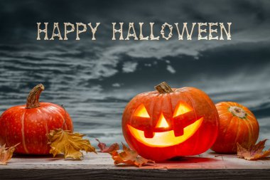 Ekim ayının ışıltılı balkabağı, balkabağı, balkabağı, kuru yapraklar, gri gökyüzüne karşı. Ahşap arka plan. Mutlu Cadılar Bayramı.