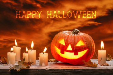 Cadılar Bayramı 'nın ışıltılı balkabağı, sonbahar yaprakları ve ahşap arka planda yanan mumlar. Kıpkırmızı, uğursuz bulutlu bir gökyüzü.